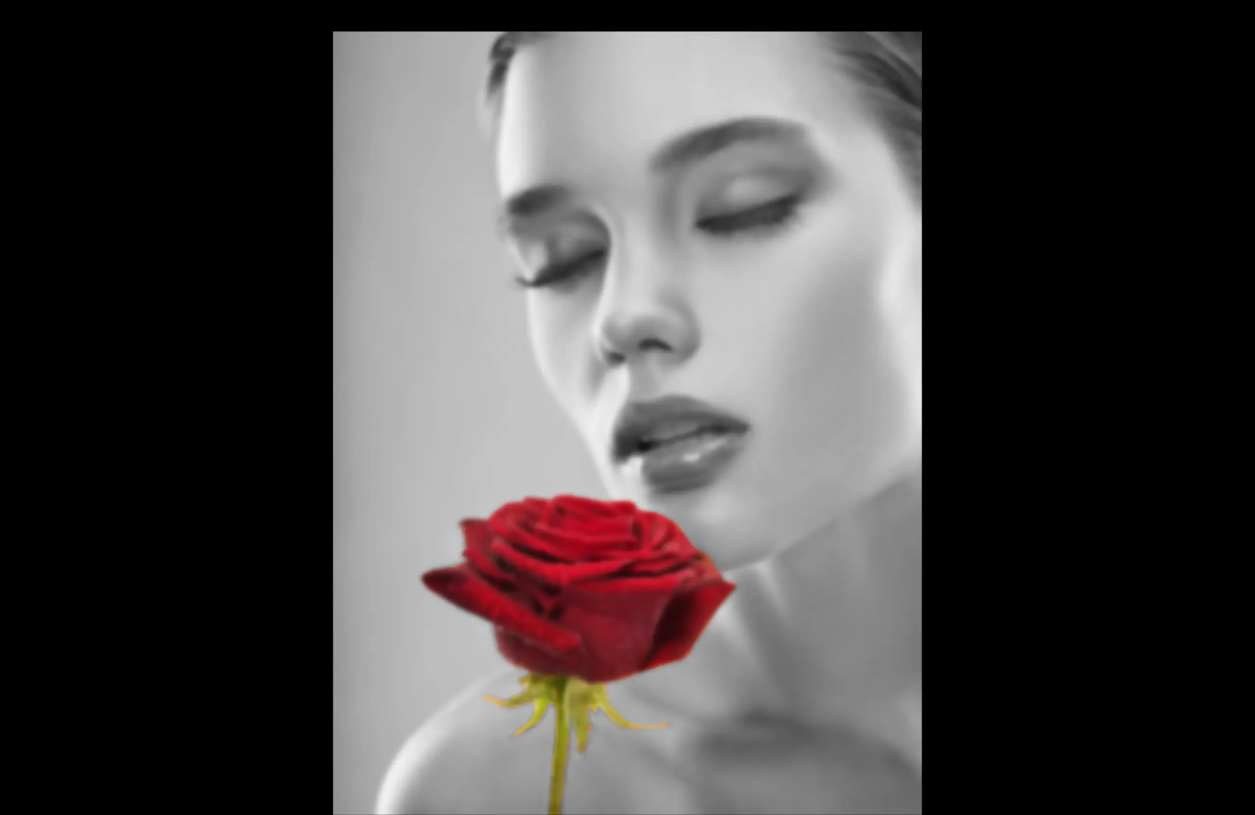 A black and white portrait of a woman with her eyes closed, holding a vibrant red rose, with a selective color effect.