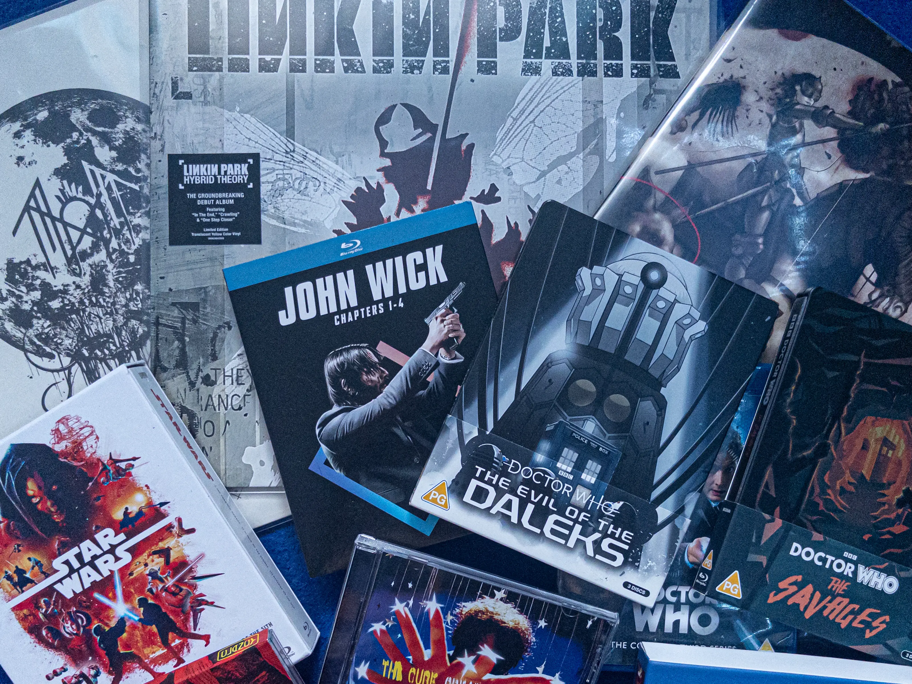 An overhead shot of a hobbyist's collection of physical entertainment merchandise, including music, movies, and TV shows.